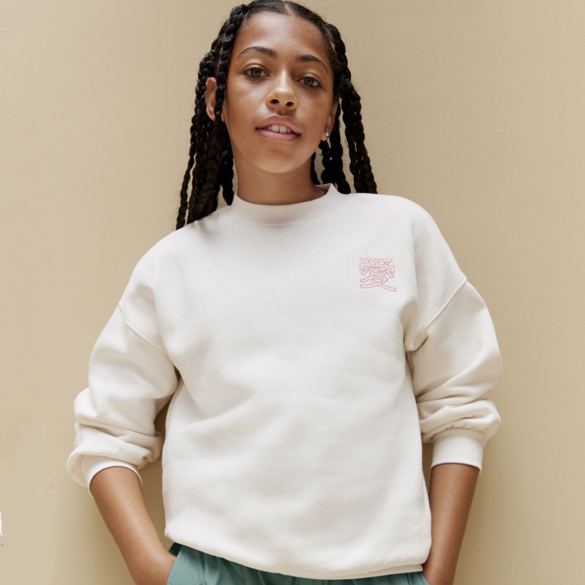 Girl wearing slogan white sweatshirt and green trousers 