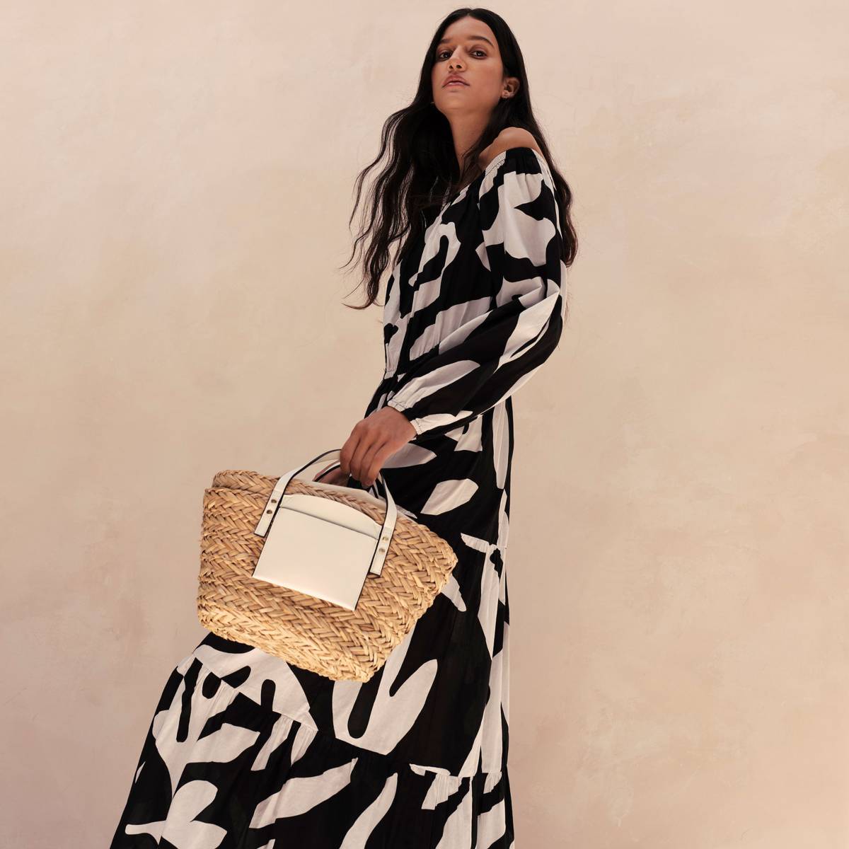 Woman wearing black and white maxi dress and straw bag 