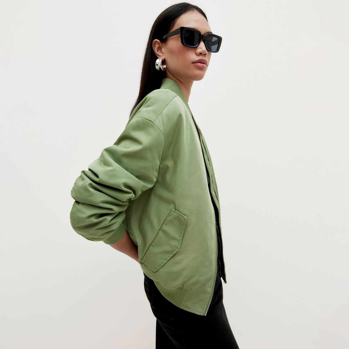 Woman wearing green bomber jacket and black pants