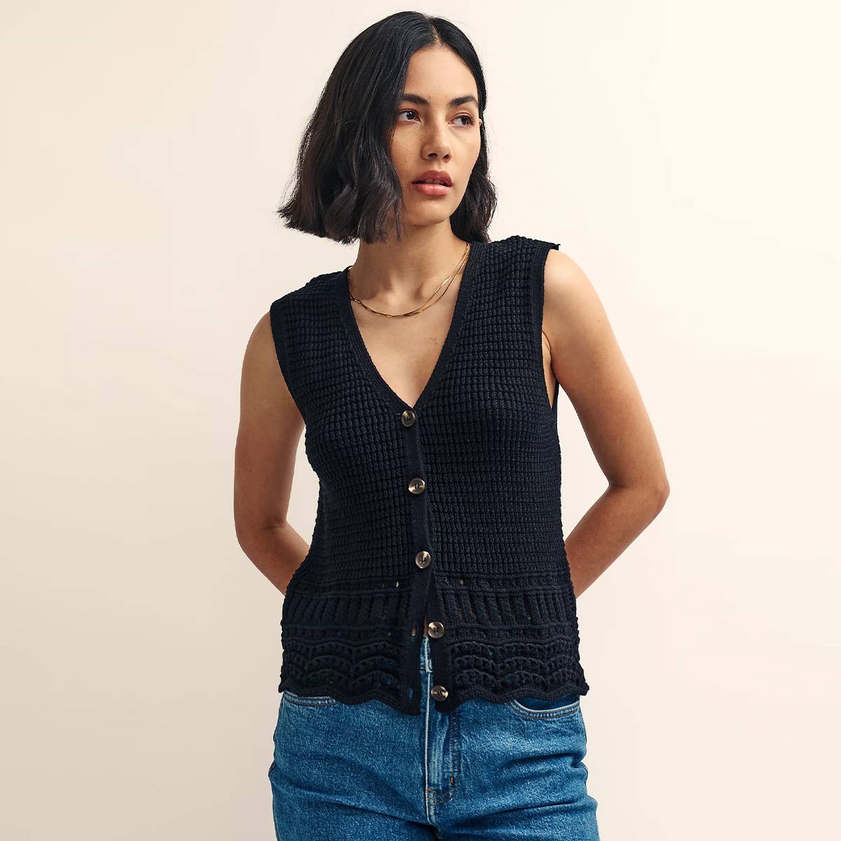Woman wearing black sleeveless cardigan and blue jeans 