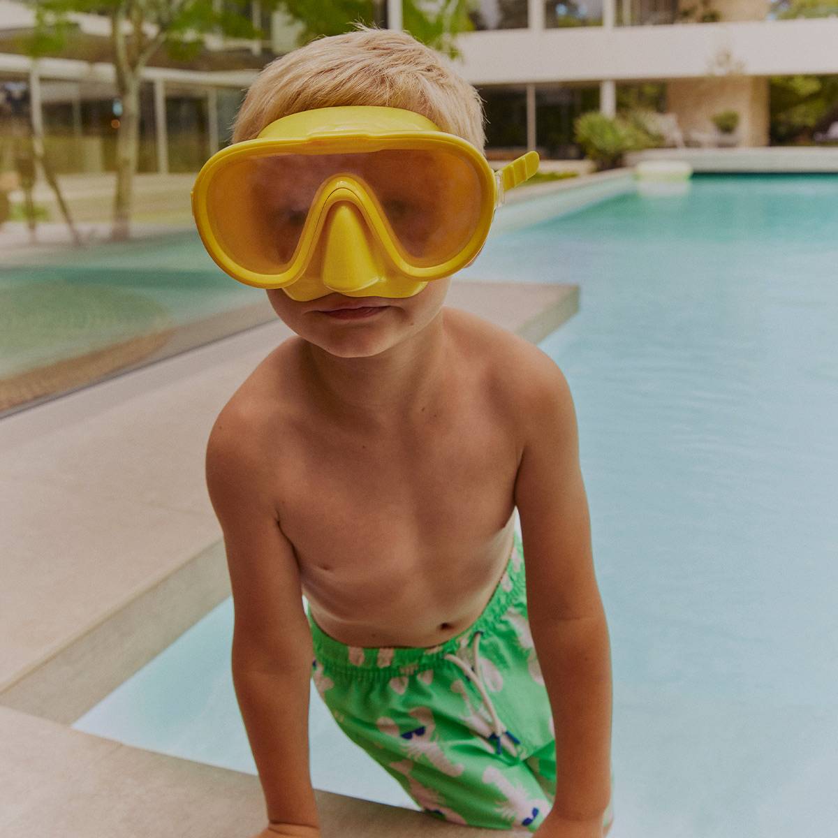 Boy wearing green swim shorts and yellow goggles 